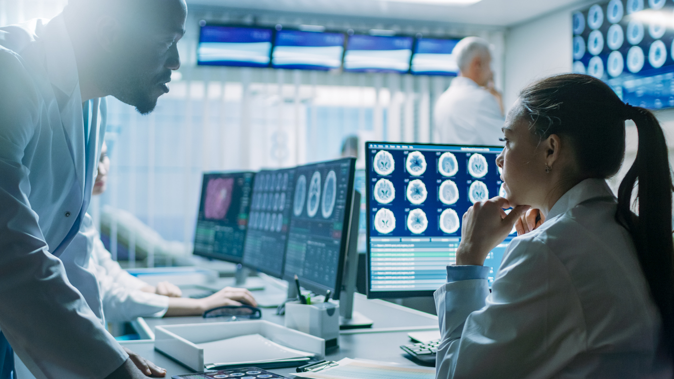 a man and a woman discussing the brain scans on a computer screen in front of them