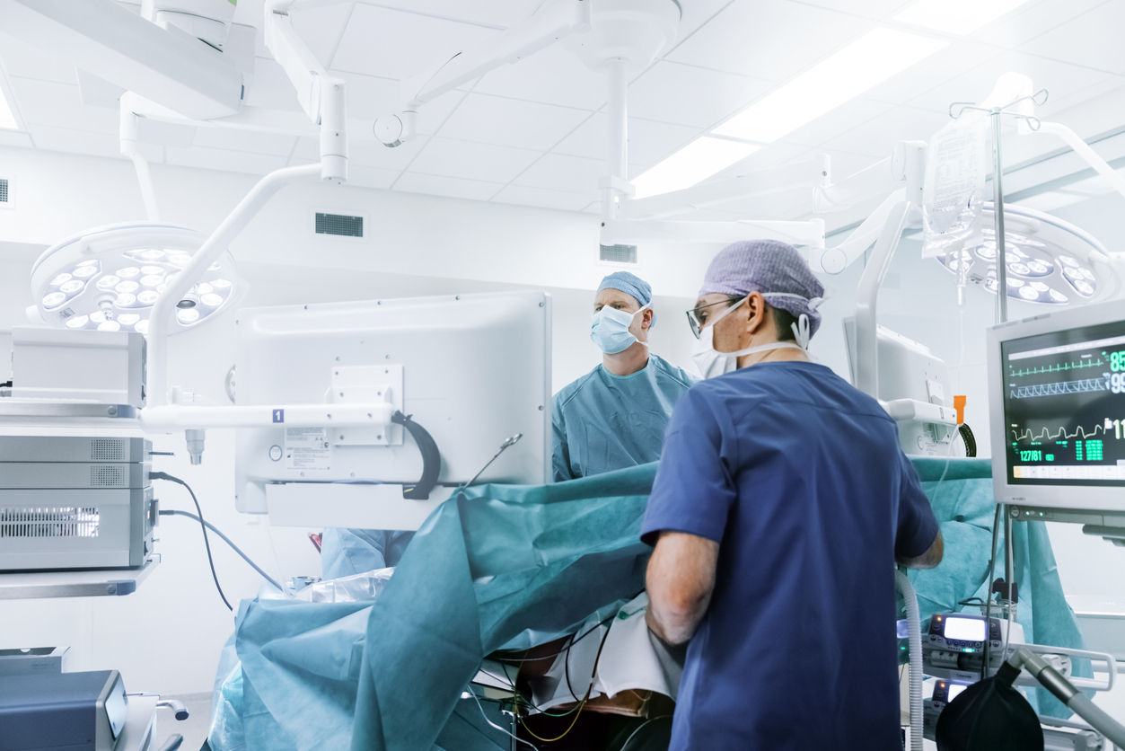 two doctors wearing scrubs and performing surgery in an operating room