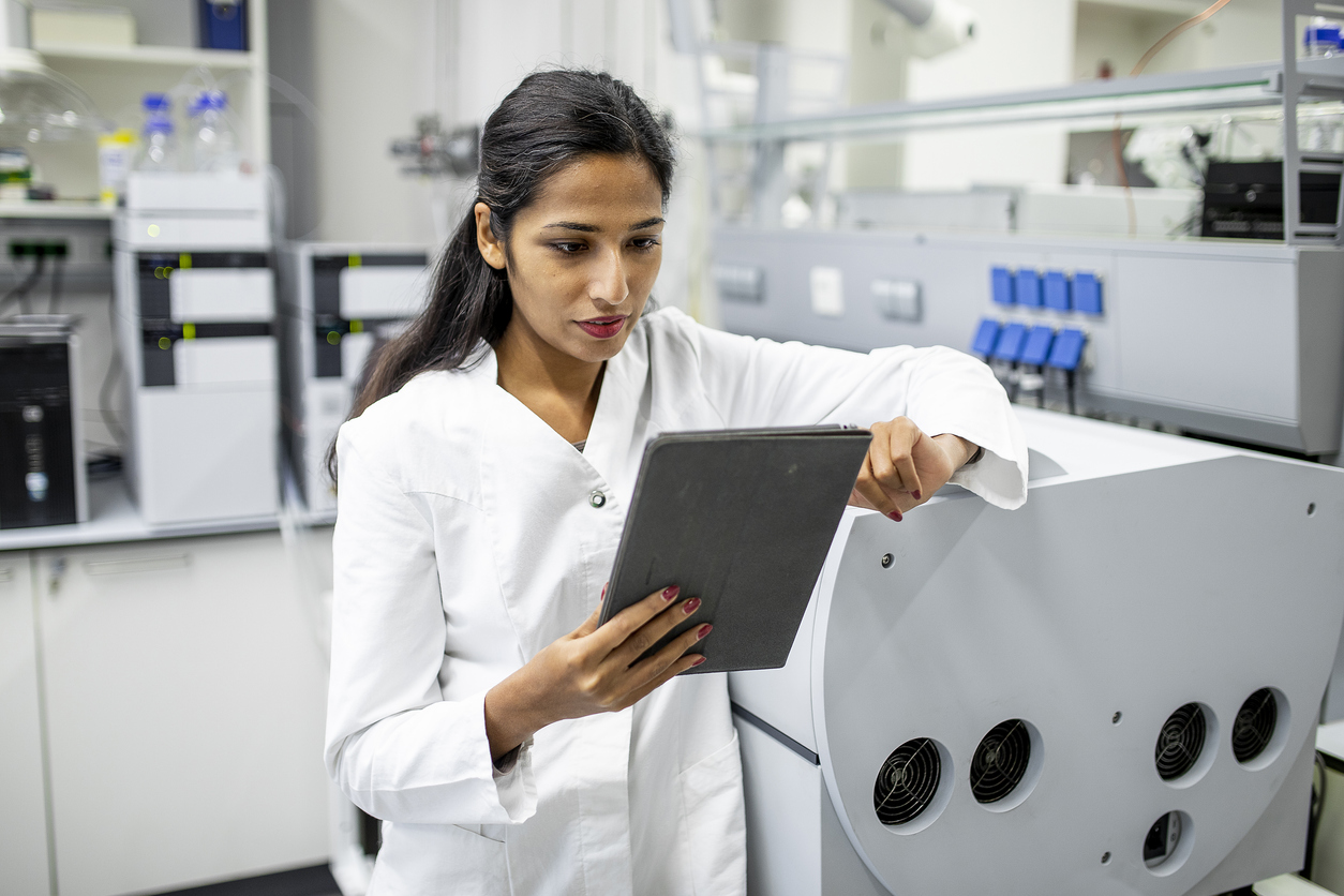 a woman wearing a lab coat in a laboratory holding a tablet