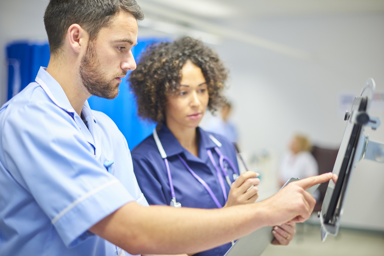 two medical professionals looking at a computer screen in a hospital room