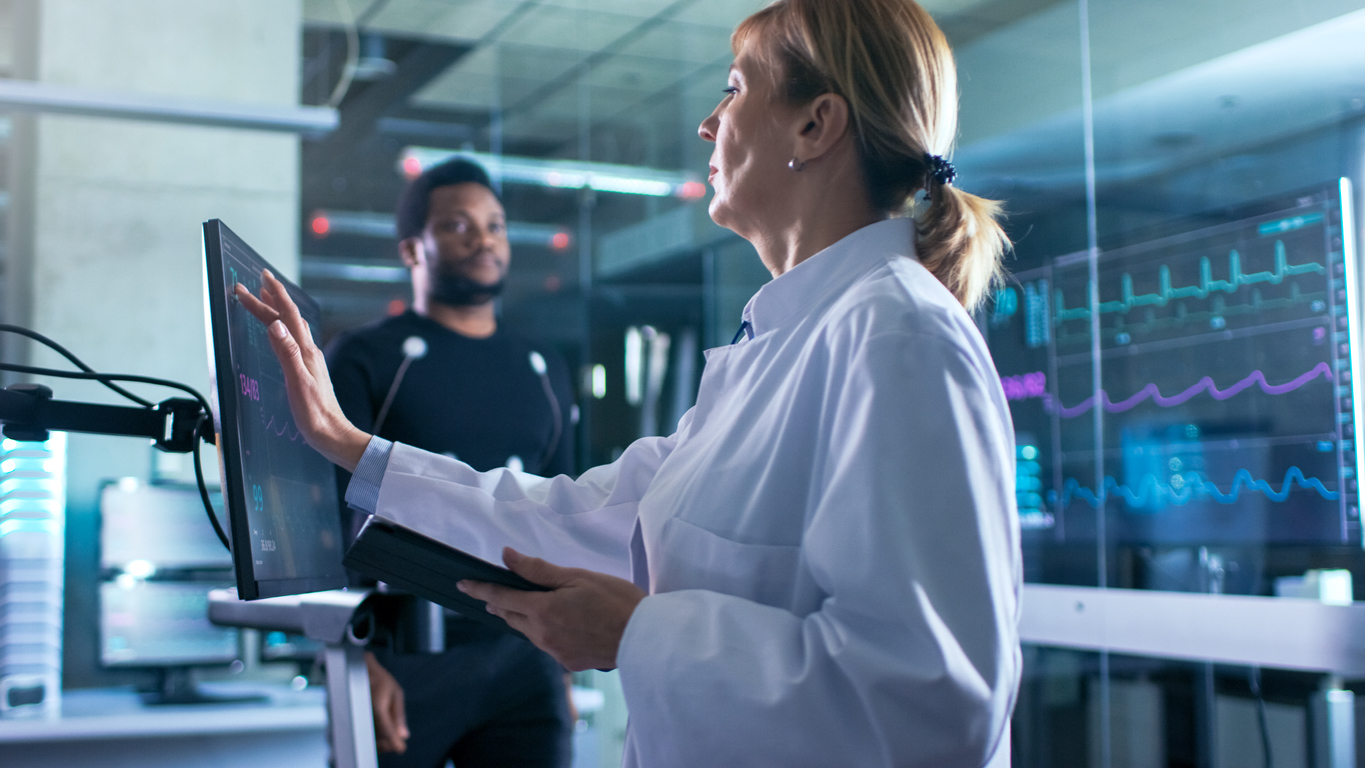 doctor using her computer to collect IoT data from a patient