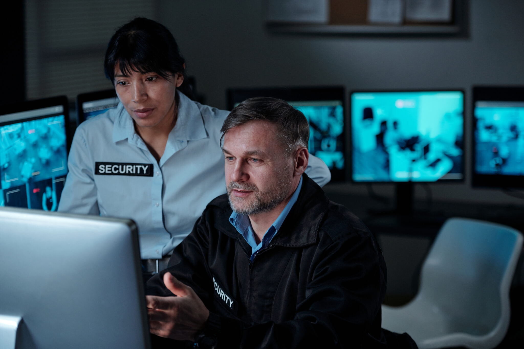 A financial services industry IT security employee and physical security employee reviewing live CCTV footage and also viewing IoT devices that are part of the building management and building security systems that the Cylera platform has discovered and assessed for cyber vulnerabilities and risks.