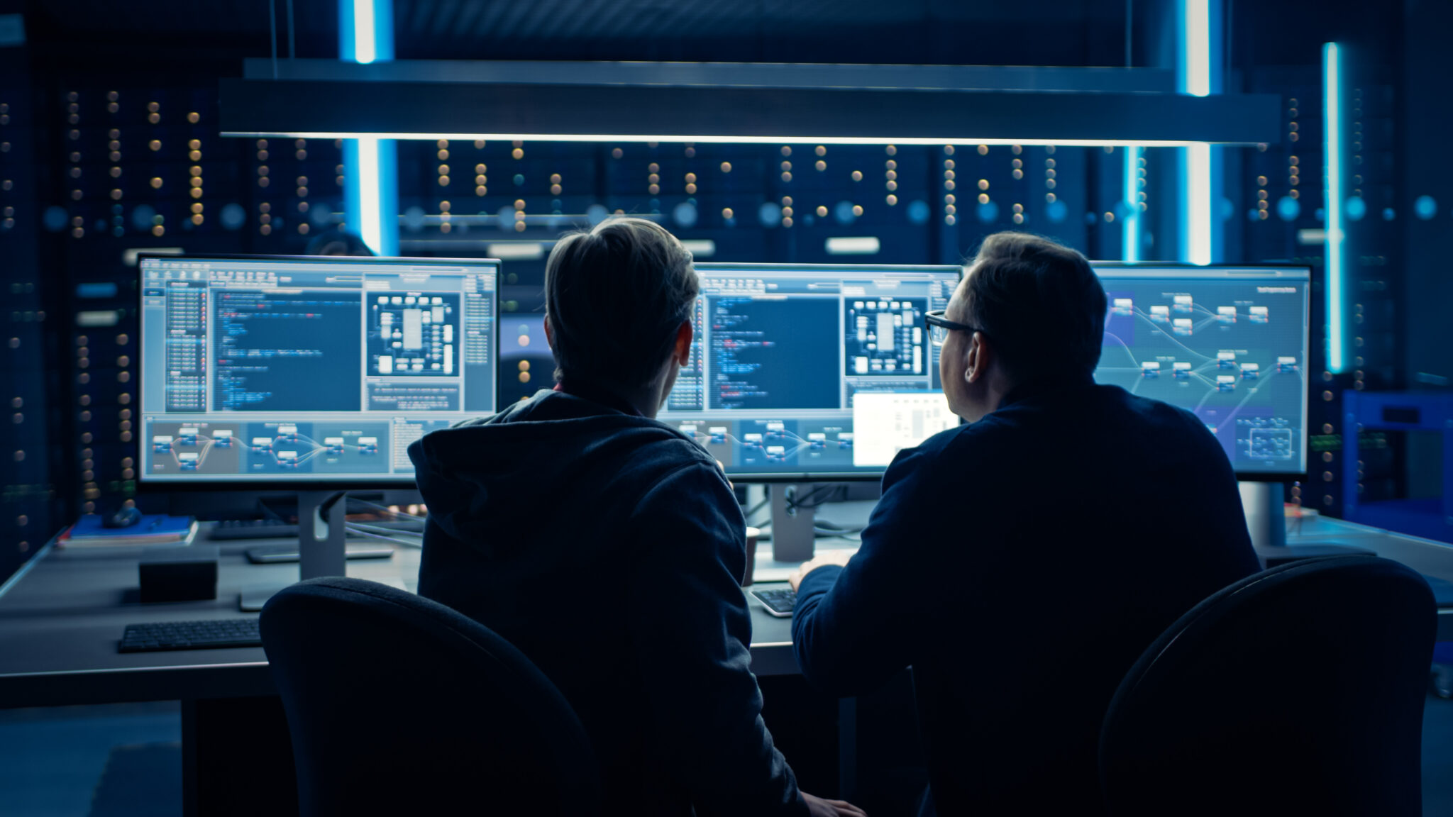 Financial services industry cybersecurity analysts monitoring real-time IoT device tracking and security posture on multiple screens and leveraging Cylera’s analytics to optimize IoT device usage and improve cybersecurity.