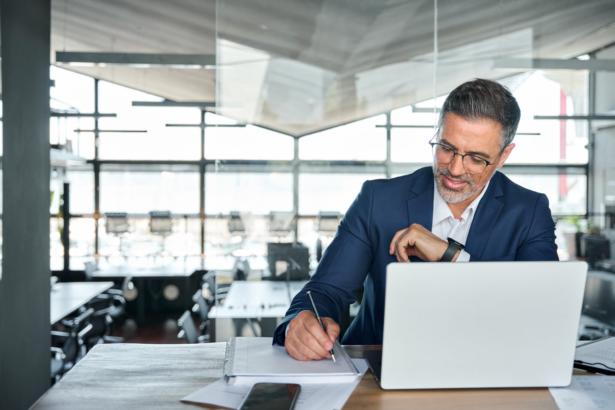 Financial services cybersecurity executive reviewing IoT compliance data on a laptop, ensuring audit efficiency and cybersecurity risk management.