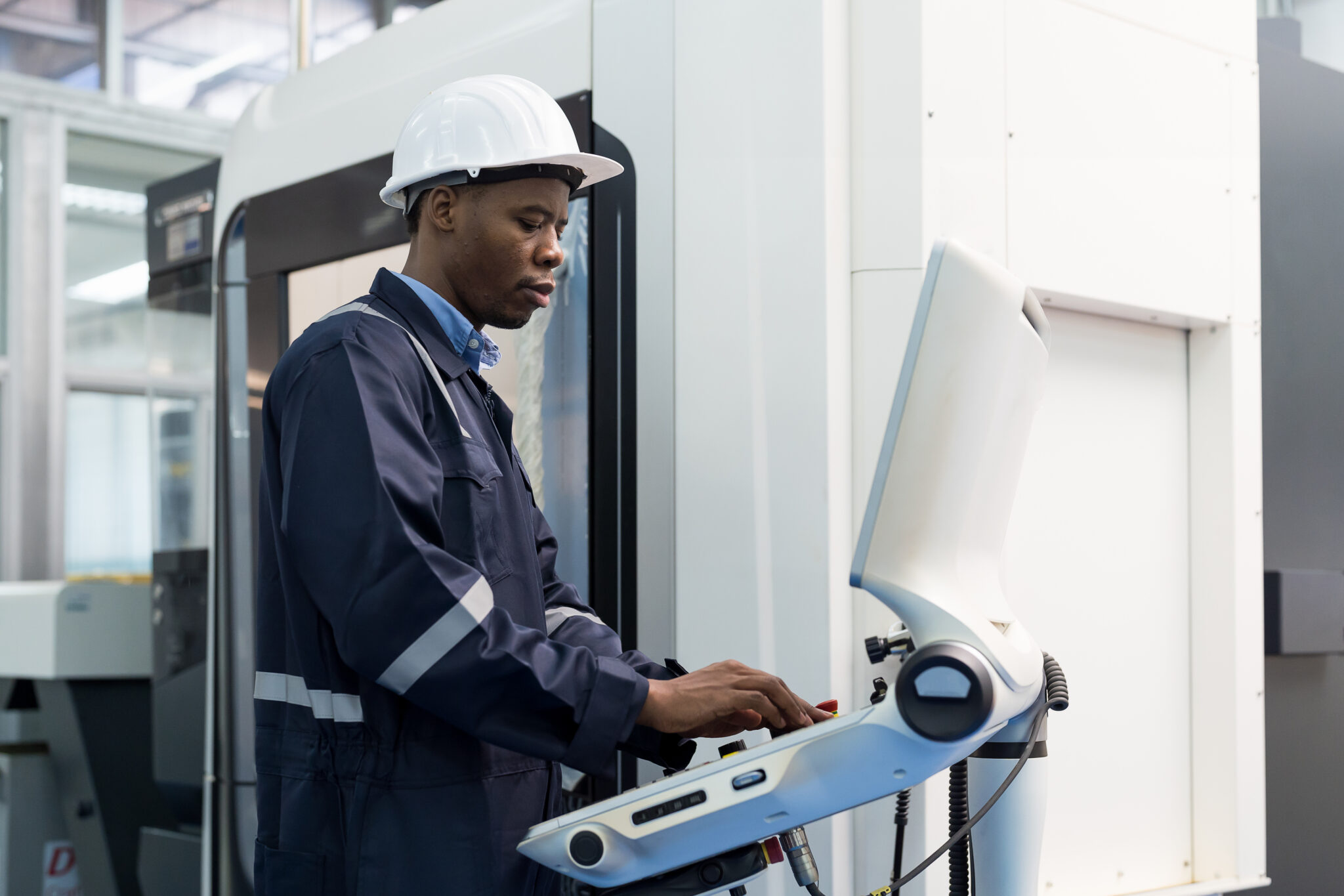 A manufacturing engineer using a production line IoT connected machine in a factory that is continuously monitored for risks and threats specific to factory environments.