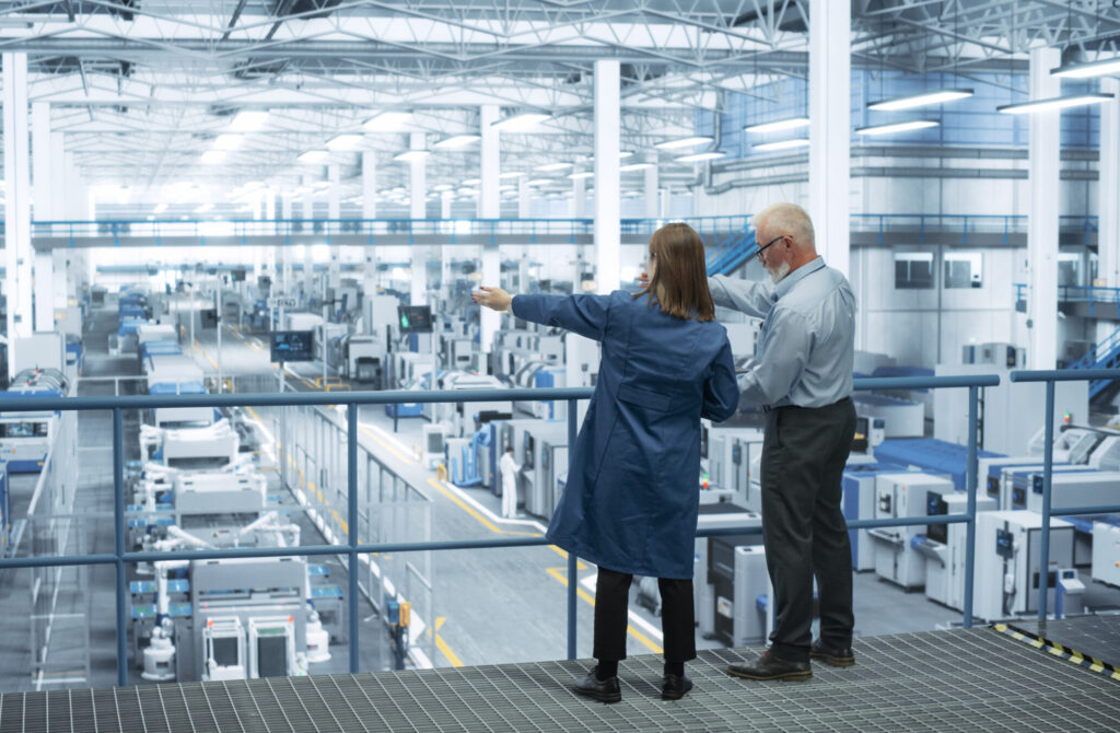 A manufacturing IT team overlooking the manufacturing floor using Cylera’s platform to monitor real-time IoT asset inventory, ensuring operational efficiency, cybersecurity, and production continuity.