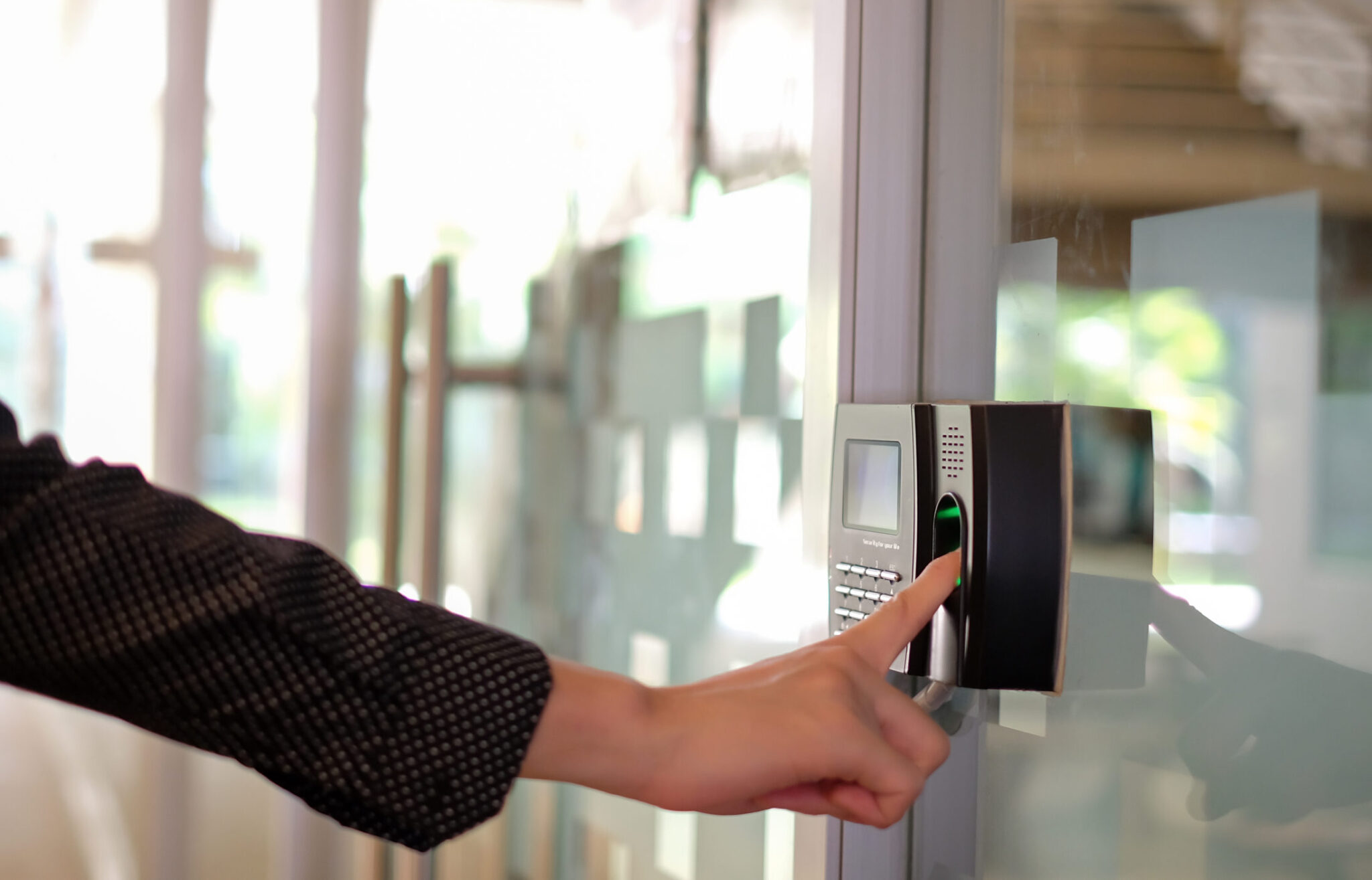 A manufacturing worker using a fingerprint scanner that is used to secure access to buildings, that uses IoT-enabled access control system that is monitored and protected by Cylera’s platform.