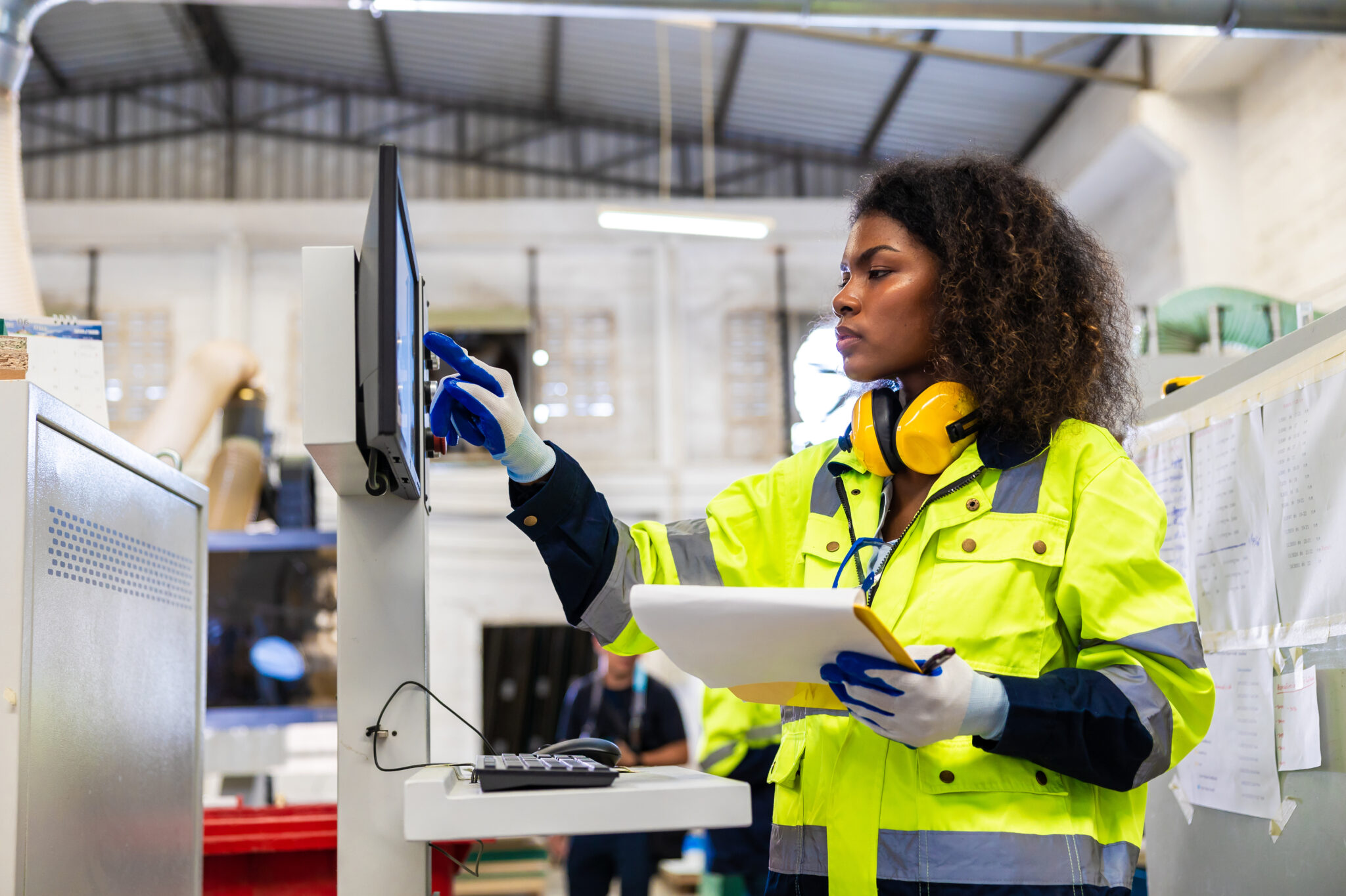 Manufacture worker in a factory using an IoT-connected machine that is monitored in real time, detecting risks and optimizing productivity.