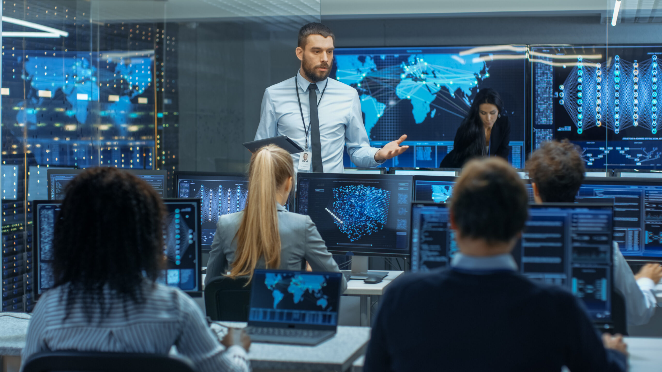 A team of cybersecurity professionals in a high-tech operations center analyzing connected IoT device security data, leveraging Cylera’s platform to manage compliance and mitigate IoT device-related risks for managed service providers (MSPs).