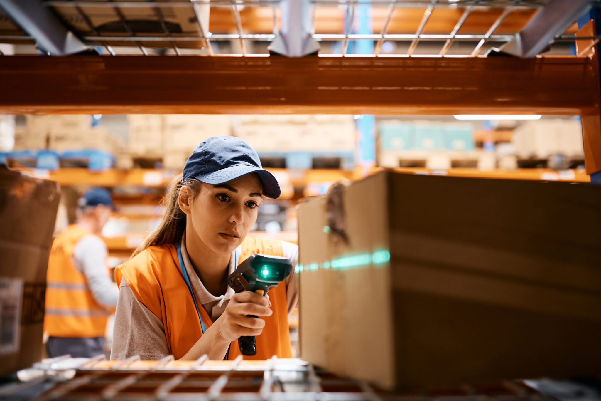 A transportation and logistics industry employee using a hand-held IoT device that is part of an IoT network and that Cylera discovers and inventories, then assesses for compliance with industry cybersecurity standards and regulations.