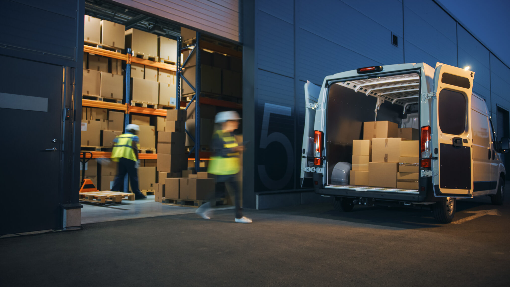 Transportation and logistics industry employees loading boxes outside a warehouse and into a delivery truck with IoT sensors and GPS trackers that the Cylera platform can discover and inventory for continuous IoT asset inventory, visibility, and security.