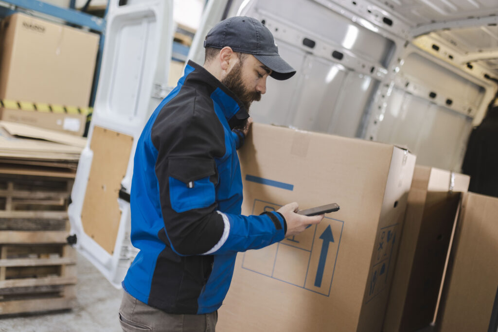 A transportation and logistics industry employee using a hand-held IoT device that is part of an IoT network and that Cylera tracks and assesses for compliance with industry cybersecurity standards and regulations.