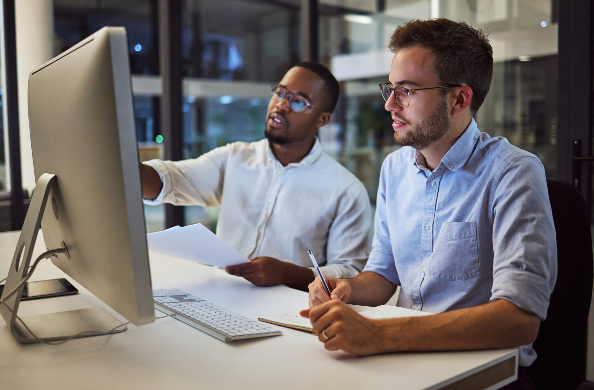 Transportation and logistics industry IT security employees viewing IoT device asset inventory, vulnerabilities, and risks discovered and managed using the Cylera platform on a computer monitor.